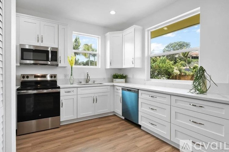 A kitchen with white cabinets and a wooden floor.