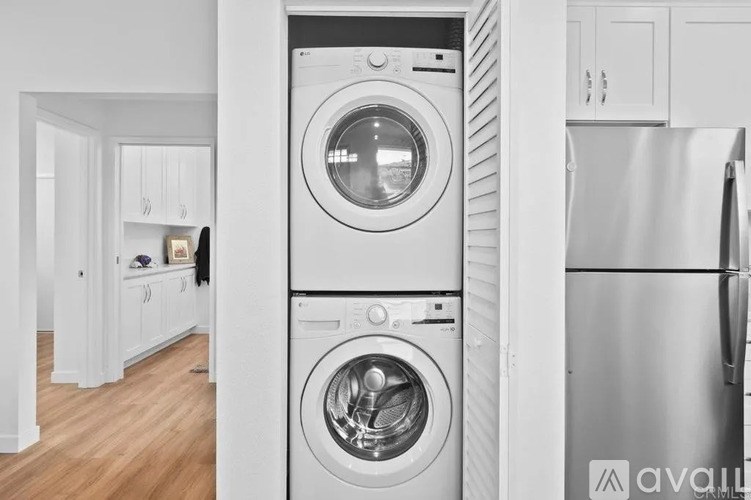 A modern laundry room with a washer and dryer built into the cabinetry.