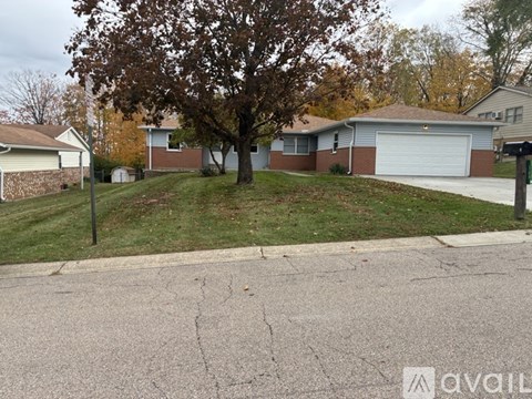 A tree in a yard with a house in the background.