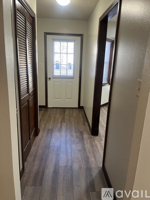 A hallway with a white door and wooden floors.