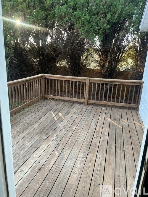 A wooden deck with a railing and trees in the background.