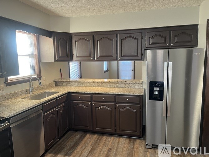 A kitchen with brown cabinets and a stainless steel refrigerator.