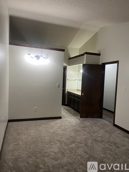 A carpeted room with a wooden door and a mirror on the wall.