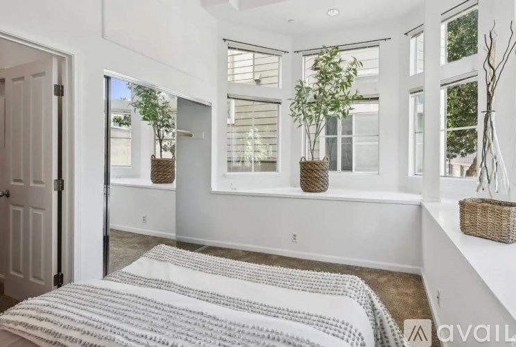 A bedroom with a bed and a window with a plant on the windowsill.