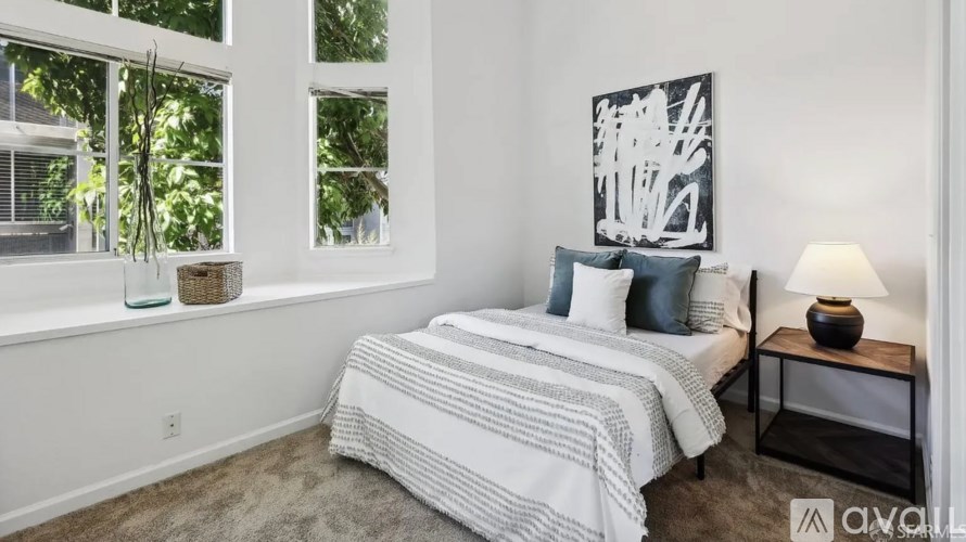 A bedroom with a bed, a nightstand, and a window.