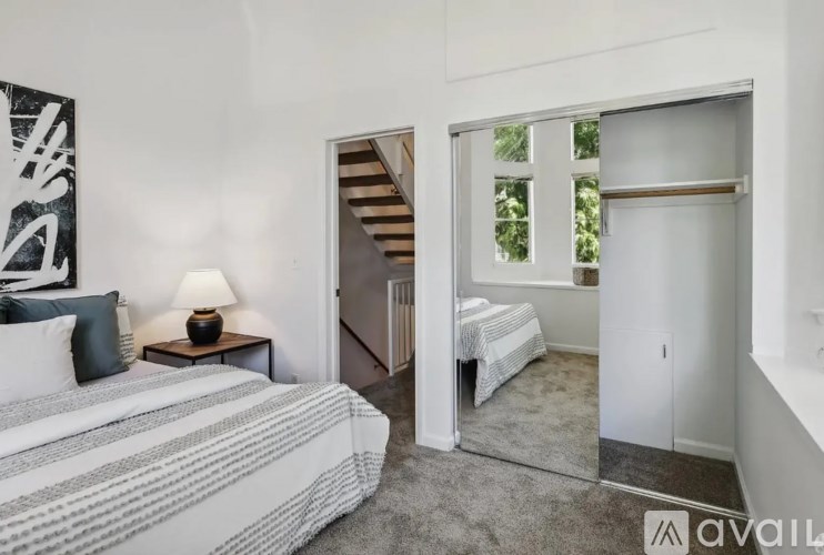 A bedroom with a bed, nightstand, and a mirror showing another bedroom.