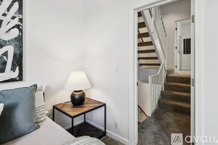 A lamp sits on a table in a room with a staircase in the background.