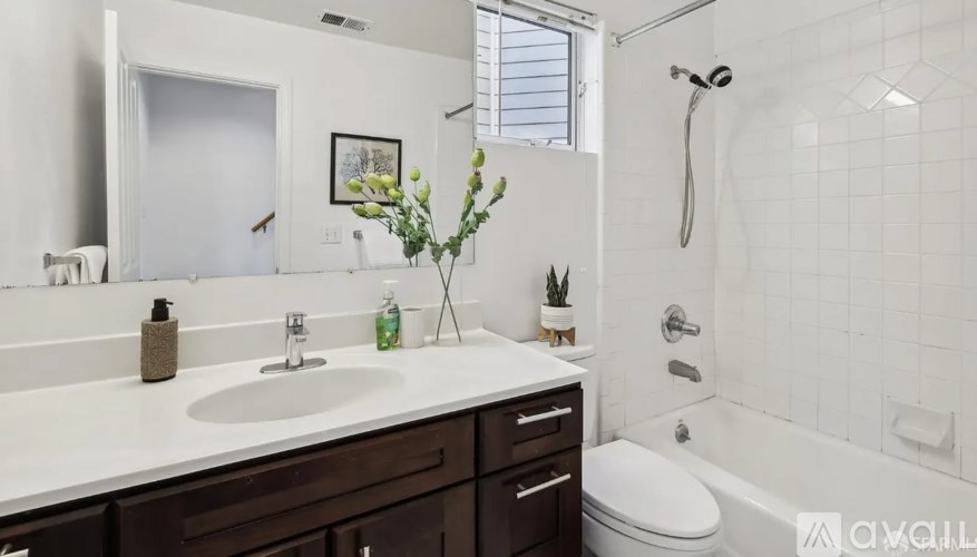 A white sink with a silver faucet and a white toilet in a bathroom.