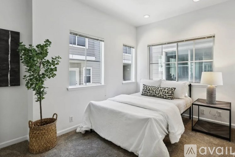 A bedroom with a white bed and a plant in a wicker basket.