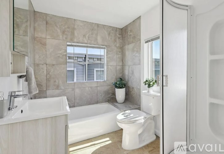 A modern bathroom with a white tub, sink, and toilet.