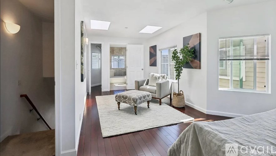 A spacious living room with a couch, ottoman, and a rug in the center.
