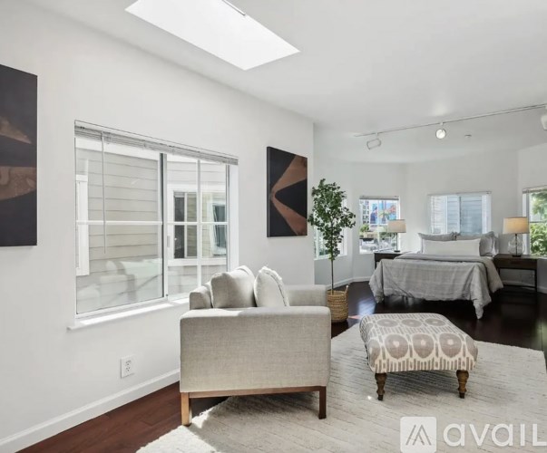 A living room with a grey couch and a rug.