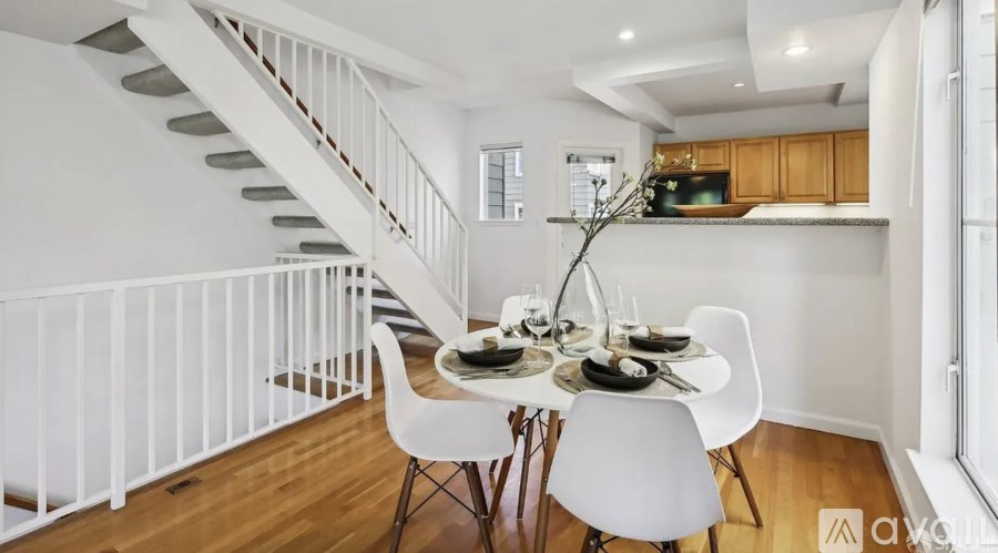 A dining table with chairs and a vase of flowers is set up in a modern kitchen.