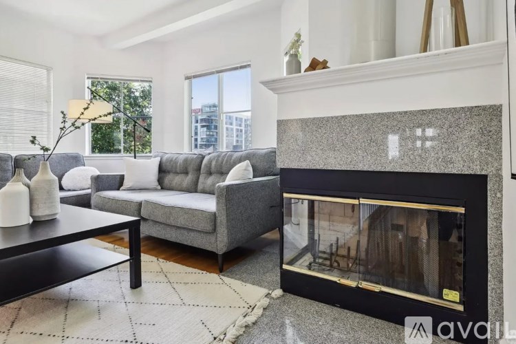 A modern living room with a grey sofa, a black coffee table, and a fireplace.