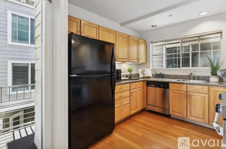 A black refrigerator in a kitchen with wooden cabinets and a stainless steel dishwasher.