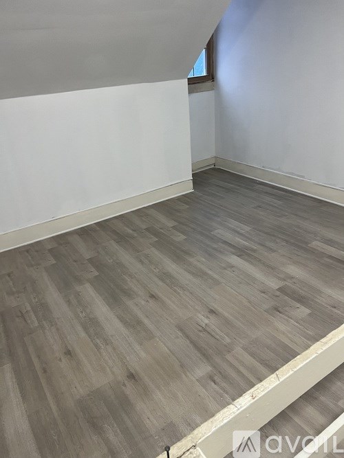 A room with wooden flooring and white walls.
