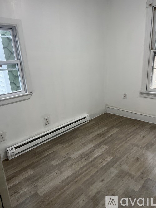 A room with a window and a wooden floor.