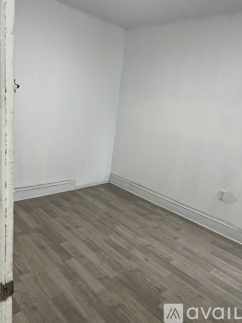 A room with wooden flooring and white walls.