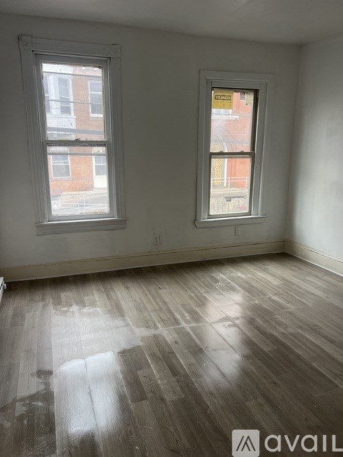 A room with two windows and wooden flooring.