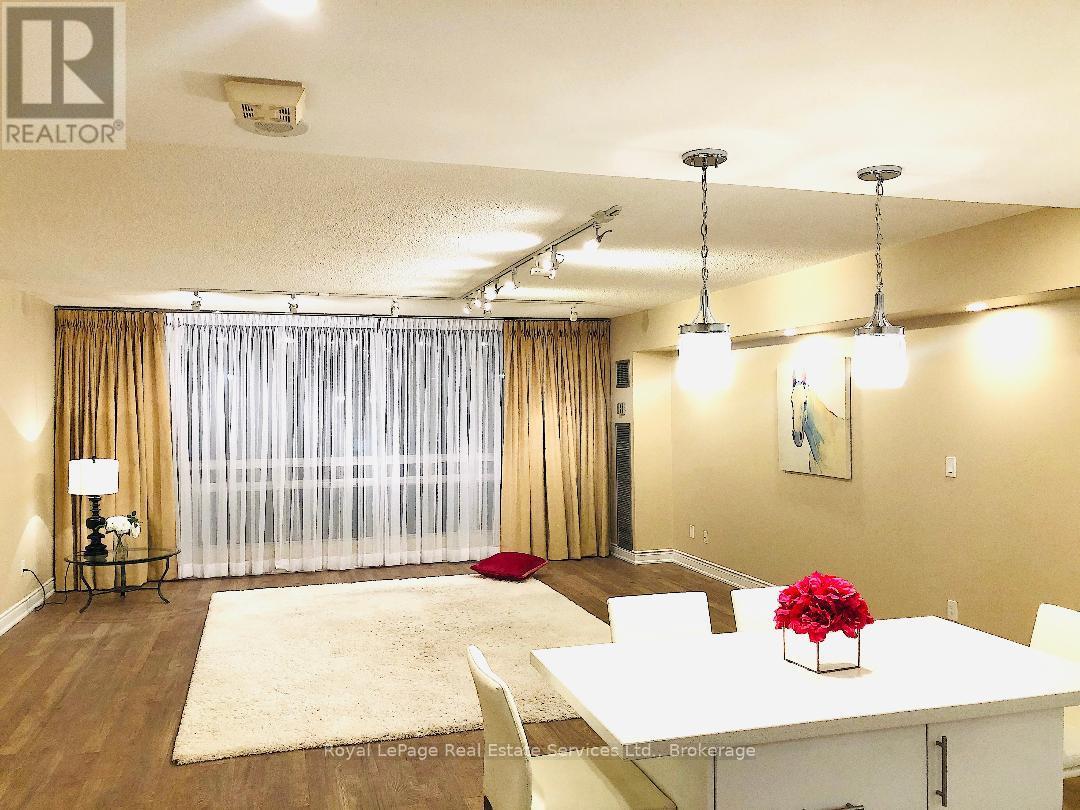 A dining room with a white table and chairs, a rug, and a painting on the wall.