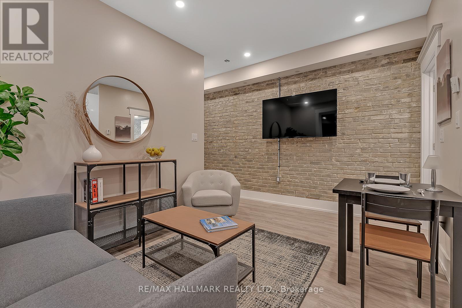 A living room with a grey sofa, a coffee table, a TV, and a mirror.