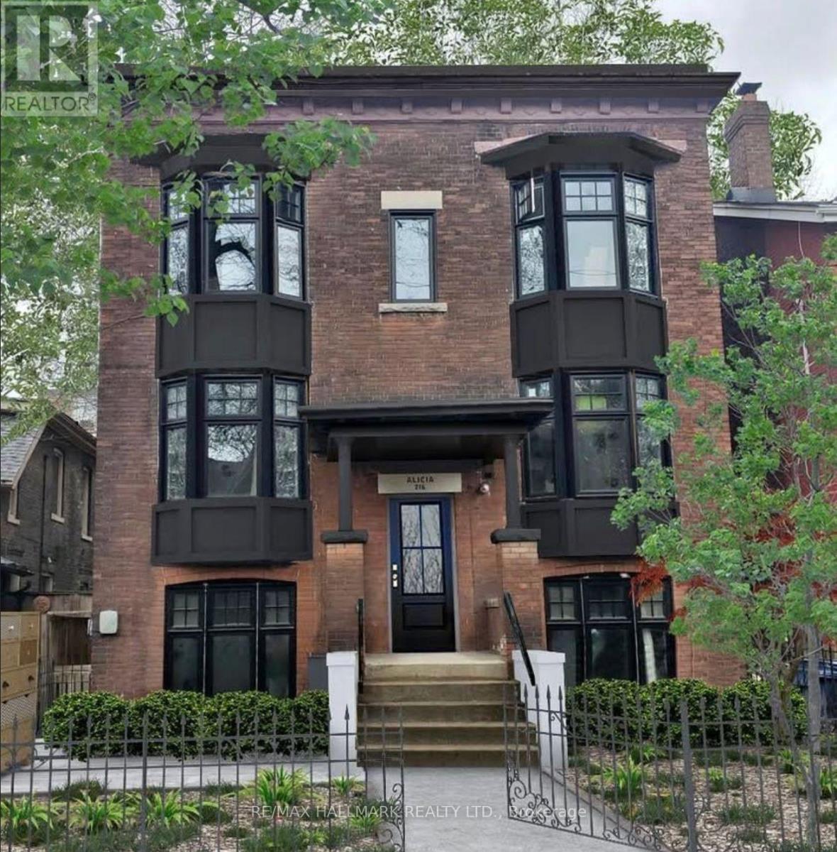 A brown brick house with a black front door and windows.