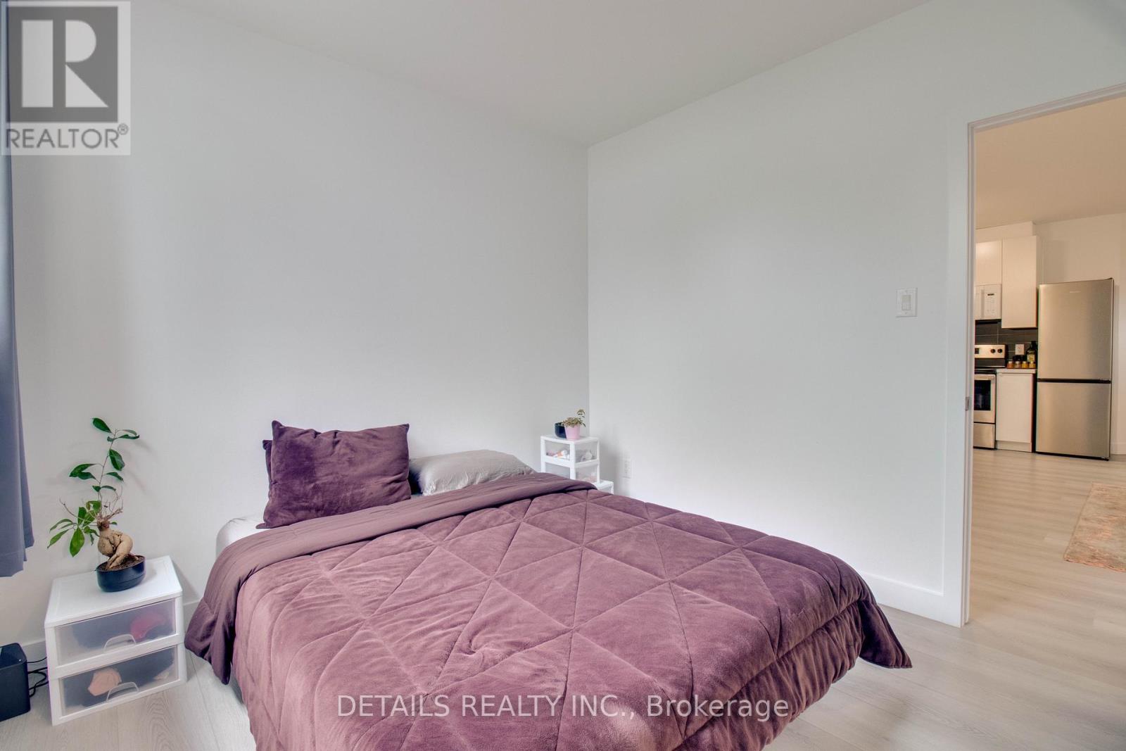 A bedroom with a bed covered in a purple comforter.