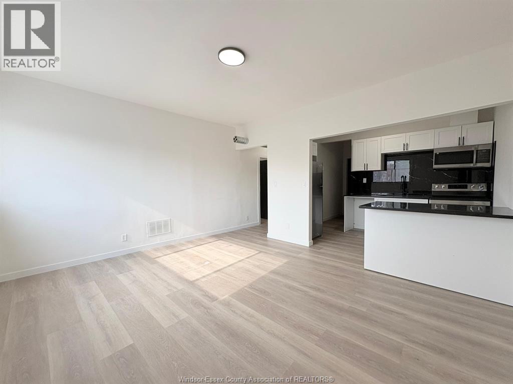A spacious room with a kitchen area in the background.