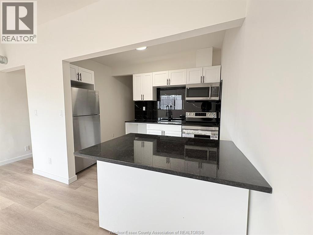 A kitchen with a black countertop and white cabinets.