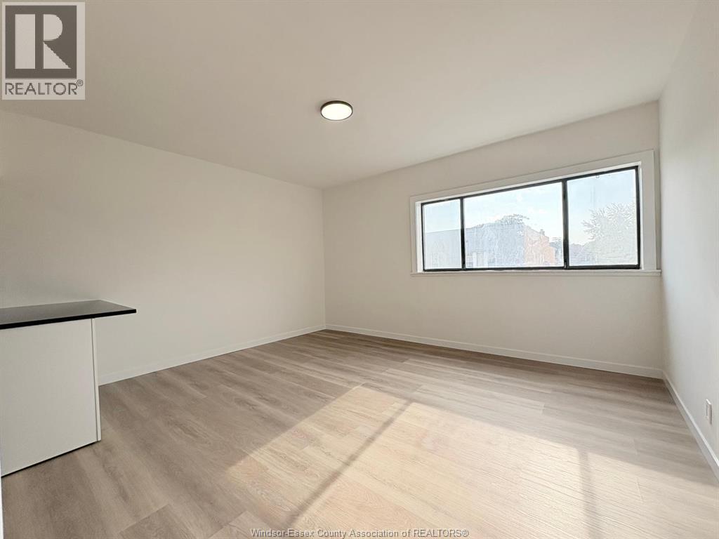 A spacious room with a large window and wooden flooring.