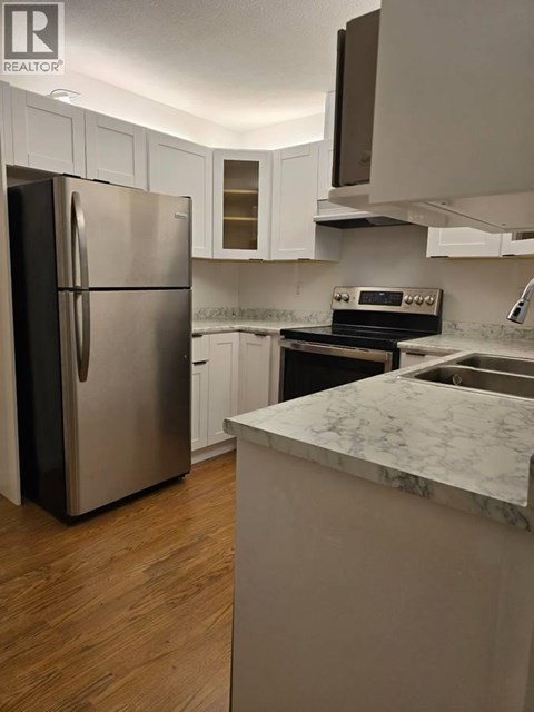 A kitchen with a refrigerator, oven, and sink.
