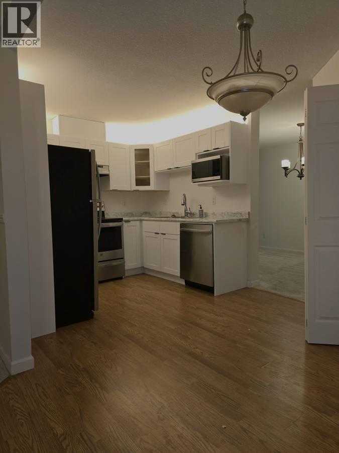 A kitchen with wooden floors and white walls.