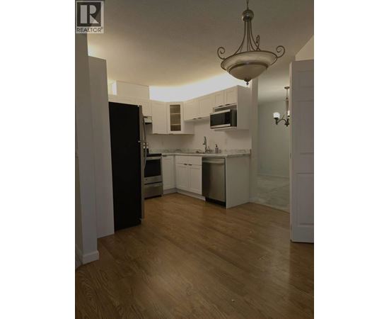 A kitchen with wooden floors and white walls.