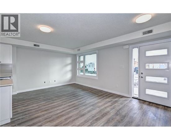 A spacious room with wooden flooring and a sliding door leading to a balcony.