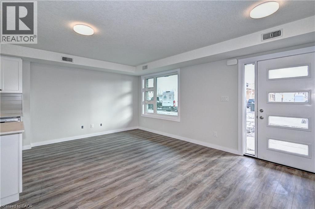 A spacious room with wooden flooring and a sliding door leading to a balcony.
