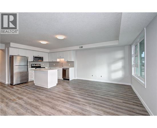 A spacious kitchen with white cabinets and a stainless steel refrigerator.