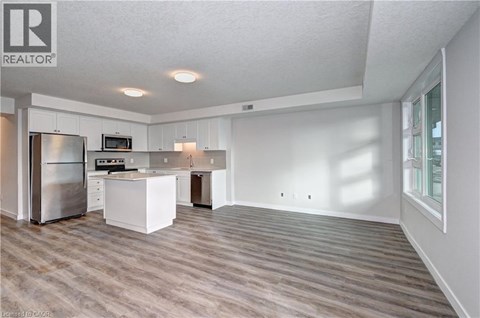 A spacious kitchen with white cabinets and a stainless steel refrigerator.