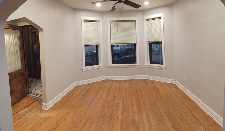 A room with wooden floors and three windows.