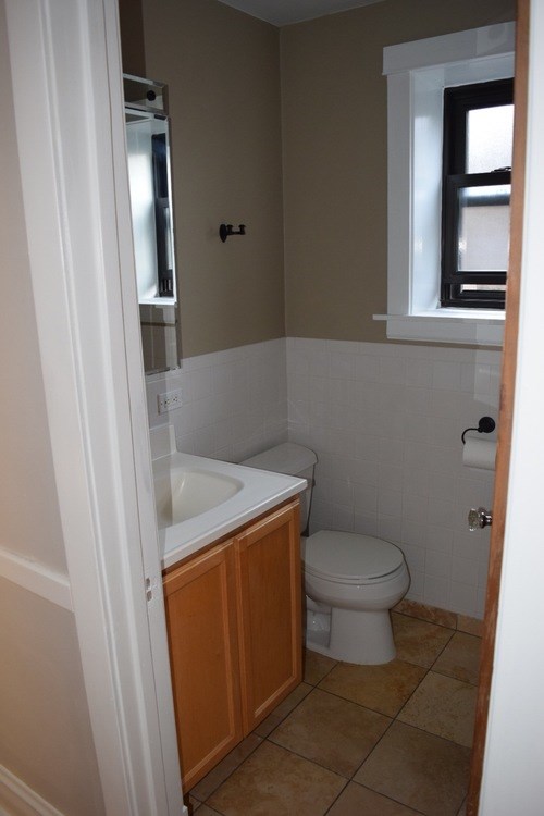 A bathroom with a toilet, sink and window.