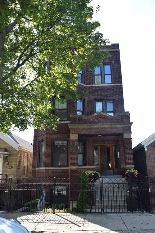 A brick house with a black gate in front.