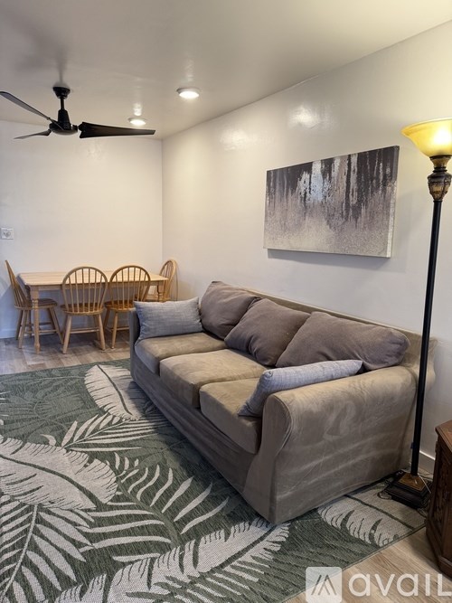 A living room with a couch, chairs, and a painting on the wall.