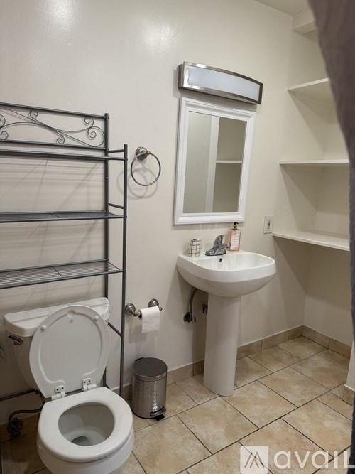 A white toilet sits next to a white sink in a small bathroom.