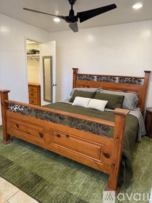 A bed with a wooden headboard and footboard with a green and black patterned bedspread and pillows.