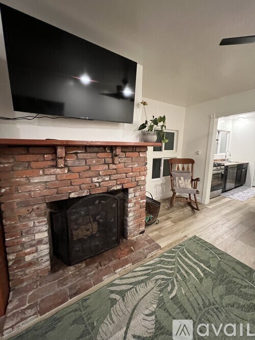 A living room with a brick fireplace and a flat screen TV mounted above it.