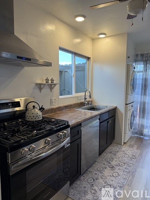 A kitchen with a black stove top oven and black cabinets.