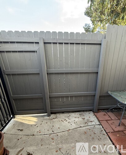 A grey fence with a bench in front of it.