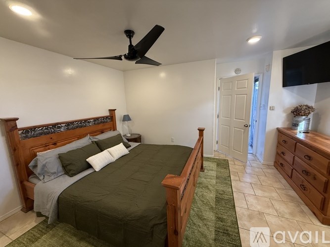 A bedroom with a bed, dresser, and ceiling fan.