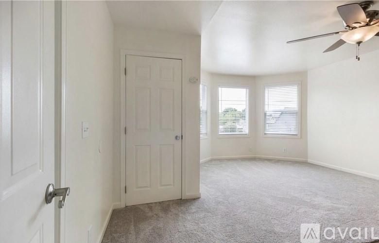 A room with a ceiling fan and a door leading to another room.