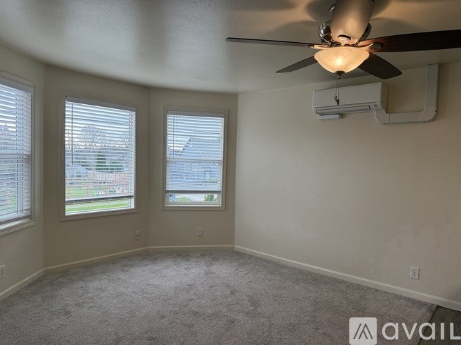 A room with a ceiling fan and two windows.