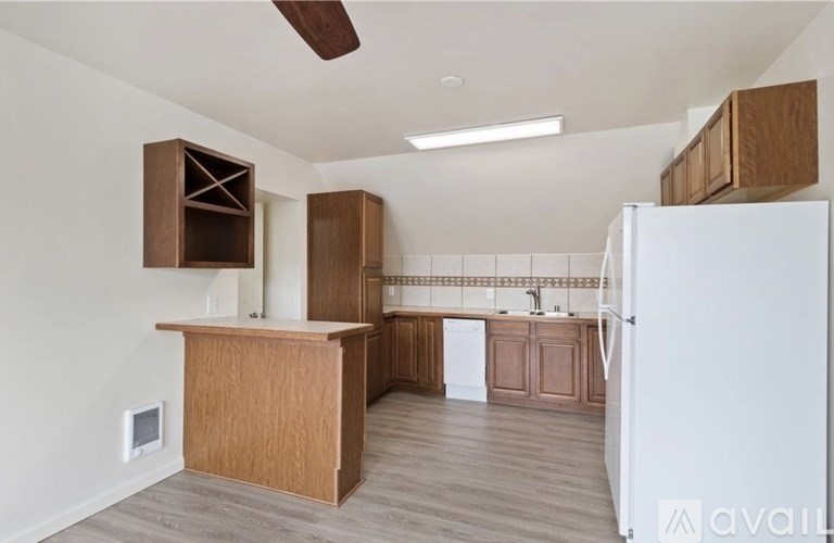 A kitchen with a white refrigerator, wooden cabinets, and a ceiling fan.